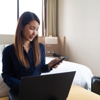 Asian businesswoman using laptop working in hotel room remotely on her business travel