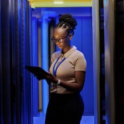 Woman in server room holding computer tablet